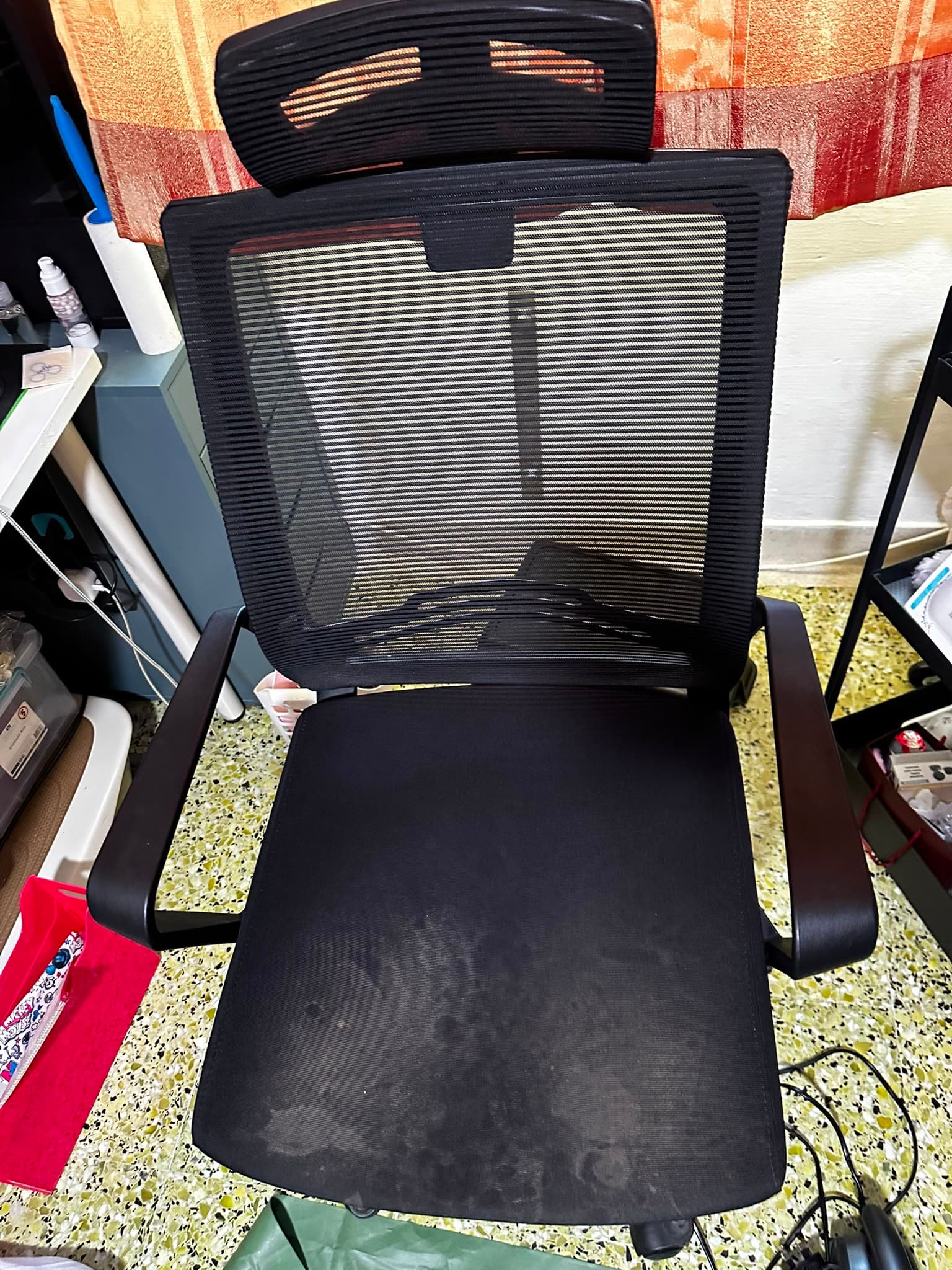 Black mesh office chair before cleaning, with marks on the seat